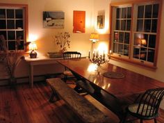 a dining room table with candles on it in front of two windows and some chairs