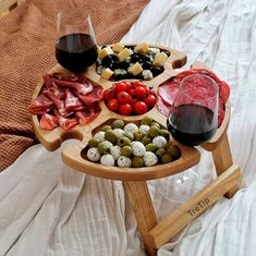 a wooden tray filled with different types of food and wine glasses on top of it