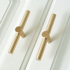 two brass handles on white doors with gold knobs in the middle and one has a round handle