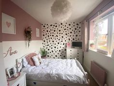 a bedroom decorated in pink and white with polka dots on the walls, bedding, dressers, and chest of drawers