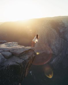 a woman standing on the edge of a cliff