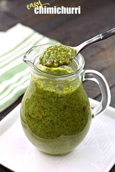 a glass jar filled with pesto sauce on top of a white plate next to a spoon