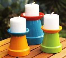 three candles sitting on top of a wooden table next to each other in different colors