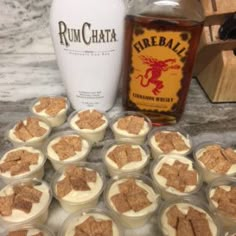 there are many desserts in plastic cups next to a bottle of rumchata