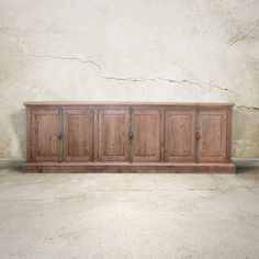 a large wooden cabinet sitting on top of a cement floor next to a white wall