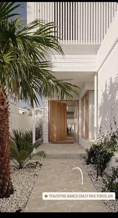 the front entrance to an apartment building with palm trees and gravel path leading up to it