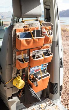 the back end of a car with several items in it and an orange bag hanging from the side