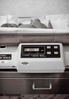 a baby is laying on top of an inclosure in a hospital bed with its head resting on the scale