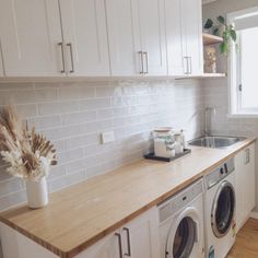 a washer and dryer sitting in a kitchen next to a window with white cabinets