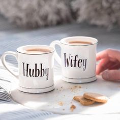 two coffee mugs with the words hubby and wife written on them next to cookies