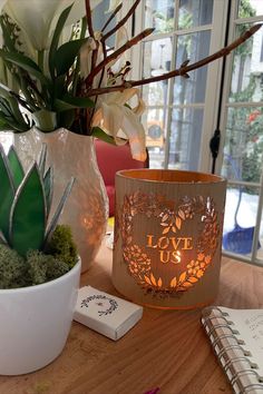 A wood and glass lantern carved with hearts and leaves saying love us lit with a candle. Perfect decor for weddings, and engagements