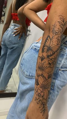 a woman's arm with flowers on it in front of a mirror and her reflection