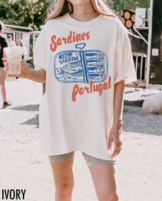 Embrace coastal charm with this vintage-inspired tee! Featuring a hand-drawn tinned sardines graphic and the phrase "Sardines, Portugal," this shirt brings a touch of Portuguese tradition and retro style to your everyday look. We use professional quality DGT printing on all our apparel. Direct-to-garment, or DTG, is a high quality printing method that sprays ink directly onto the garment so there is no peeling or cracking. This fabulous graphic will be printed on a Comfort Colors Unisex T-Shirt. Retro Graphic Tshirt, Fish Tshirt Design, Tinned Sardines, Wedding Merch, Aesthetic Fish, Surfer Shirt, Tinned Fish, Nautical Shirt, Fish Shirt