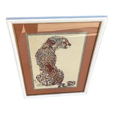 a framed painting of a cheetah sitting on the ground