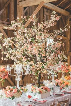 the table is set with flowers, candles and place settings for an elegant wedding reception