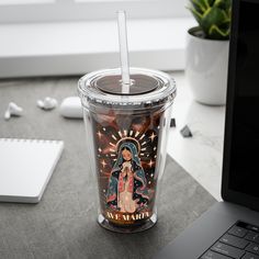 a plastic cup with a straw in it sitting on a desk next to a laptop