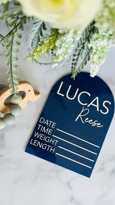 a blue luggage tag sitting on top of a white table next to a bouquet of flowers