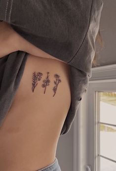 the back of a woman's stomach with three small flowers on it