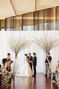 the bride and groom are getting married in front of an altar decorated with white flowers