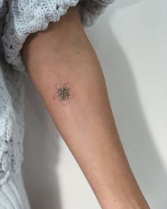 a woman's arm with a small spider tattoo on the left side of her arm