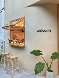 an open window on the side of a building with plants in pots and stools next to it