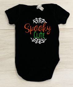 This adorable baby onesie is the perfect outfit for Halloween and fall. Available for infant, toddler and youth sizes. Your little one is sure to put a smile on anyone's face and is the perfect mix of cute and spooky! Comes in a black shirt with white cobwebs, orange and neon green lettering. Playful Black Short Sleeve Onesie, Cute Black Short Sleeve Onesie, Cute Black Cotton Bodysuit, Black Onesie For Halloween Playtime, Black Halloween Onesie For Playtime, Cute Fall Playtime Bodysuit, Cute Black Halloween Onesie, Black Cotton Halloween Onesie, Cute Black Bodysuit For Playtime