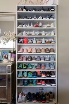 a white shelf filled with lots of shoes next to a dresser and mirror in a room