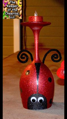 a red vase with a ladybug painted on it and a candle in the middle