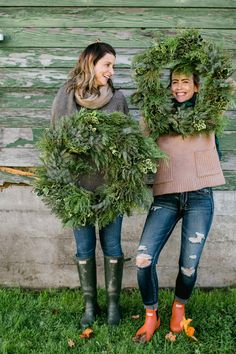 two women standing next to each other holding wreaths