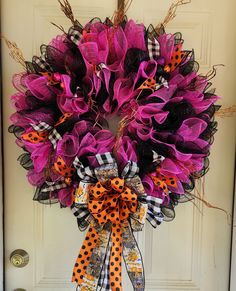 a purple wreath with black and orange polka dots on the front door, decorated with ribbon