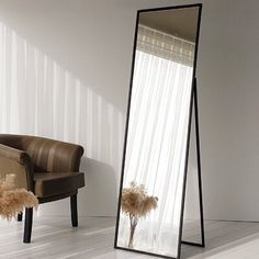 a large mirror sitting on top of a white floor next to a chair and window