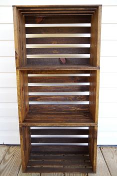 a wooden book shelf sitting on top of a wooden floor next to a white wall