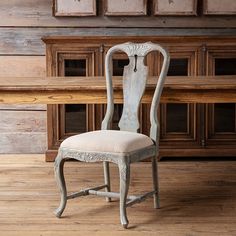 an old wooden chair sitting on top of a hard wood floor next to a wall