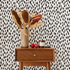 a vase filled with flowers sitting on top of a wooden table next to a wall