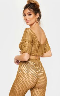 a woman in gold fishnet bodysuit posing for the camera with her hands on her hips