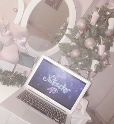 an open laptop computer sitting on top of a white desk next to a christmas tree