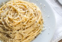 a white plate topped with pasta covered in parmesan cheese and black pepper sprinkles