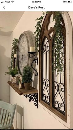 a clock mounted to the side of a wall next to a table with chairs and potted plants