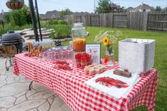 a red and white checkered table cloth with lobsters on it in the backyard