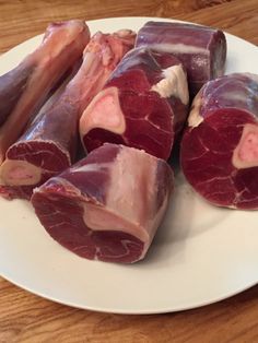 several pieces of raw meat on a white plate