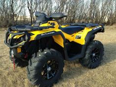 a yellow and black four - wheeler is parked in the grass with trees behind it