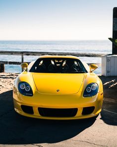 a yellow sports car parked in front of the ocean