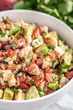 a white bowl filled with salad next to tortilla chips and avocado