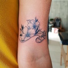 a woman's arm with flowers on it and a ribbon around the wrist tattoo