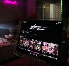 a laptop computer sitting on top of a table in front of a pink lit room