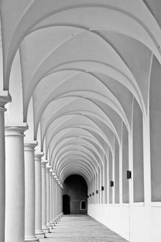 black and white photograph of an arched hallway with columns on both sides, leading into the distance