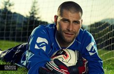 a man laying on the ground with a soccer ball in his hand and wearing gloves