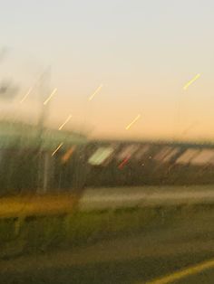 blurry photograph of an airplane in the sky at sunset or dawn, taken through a window