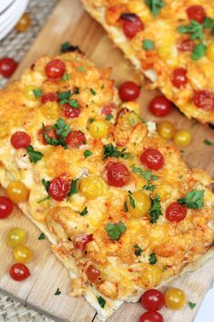 two pieces of pizza on a cutting board with cherry tomatoes and parsley