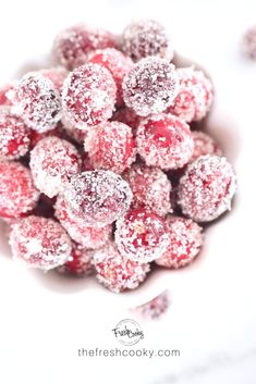 powdered sugar coated cranberry bites in a white bowl on a marble surface